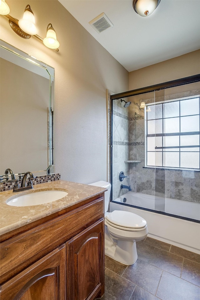 full bathroom with bath / shower combo with glass door, toilet, and vanity