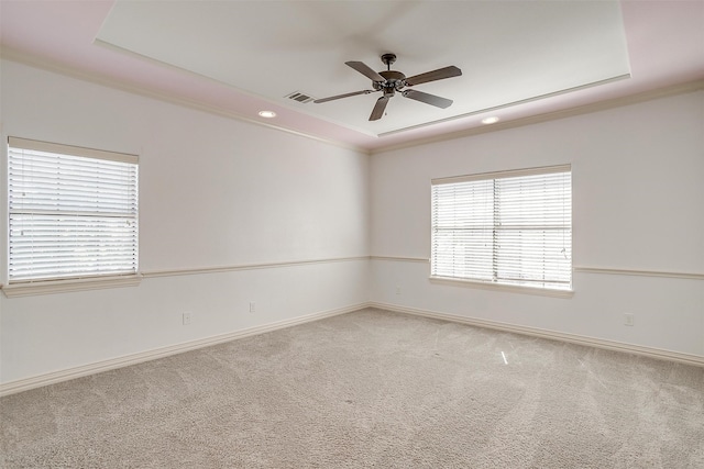 carpeted empty room with a raised ceiling, crown molding, and ceiling fan