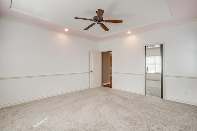 unfurnished room featuring light carpet, a raised ceiling, crown molding, and ceiling fan