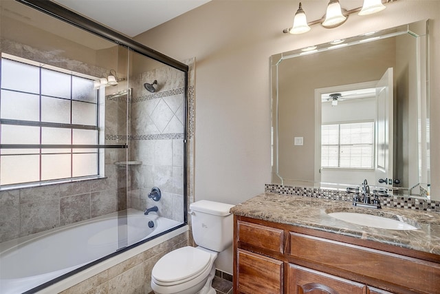 full bathroom with ceiling fan, shower / bath combination with glass door, vanity, and toilet