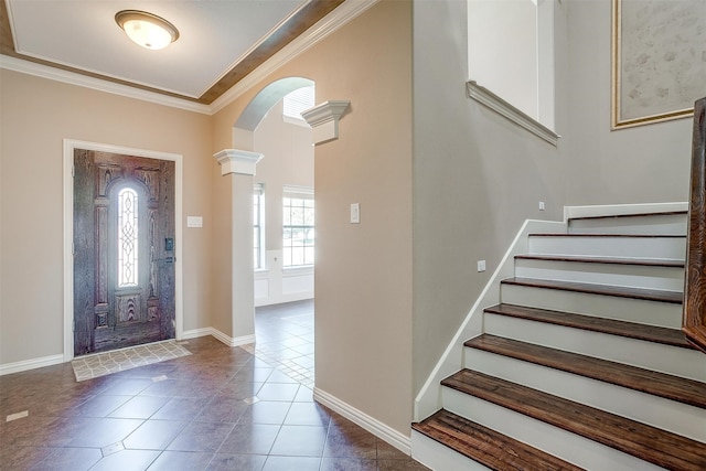 foyer entrance featuring dark tile patterned flooring, ornate columns, and crown molding