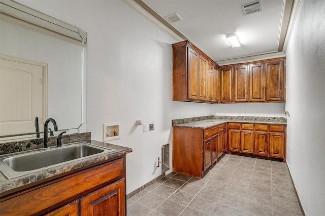 washroom with light tile patterned flooring, sink, cabinets, hookup for a washing machine, and crown molding