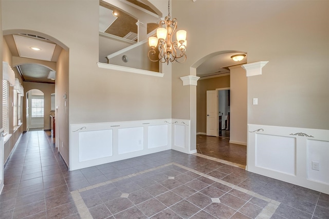 tiled empty room featuring beam ceiling, a chandelier, and ornate columns