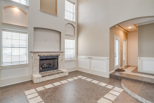 unfurnished living room featuring a high ceiling, plenty of natural light, and crown molding