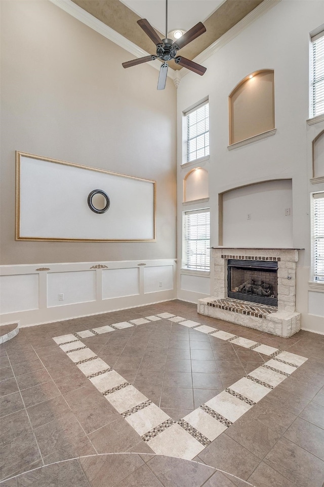 unfurnished living room featuring a fireplace, a towering ceiling, and crown molding