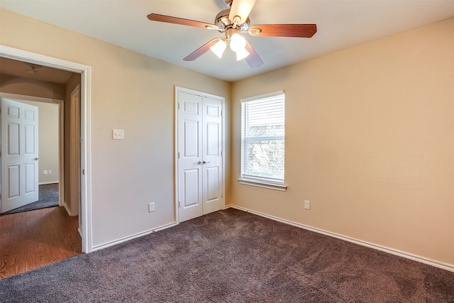 unfurnished bedroom featuring ceiling fan, a closet, and dark carpet