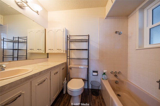 full bathroom with vanity, tiled shower / bath, wood-type flooring, toilet, and a textured ceiling