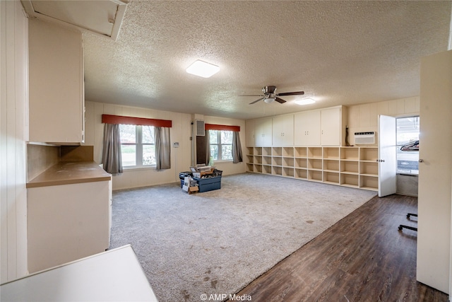 interior space featuring dark hardwood / wood-style floors, an AC wall unit, a textured ceiling, and ceiling fan