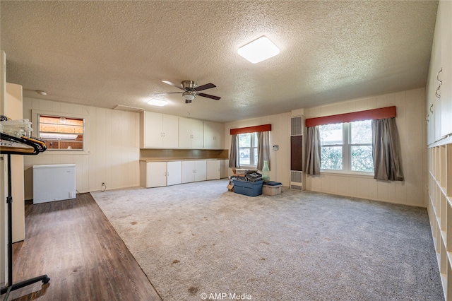 unfurnished living room with dark wood-type flooring, ceiling fan, and a textured ceiling