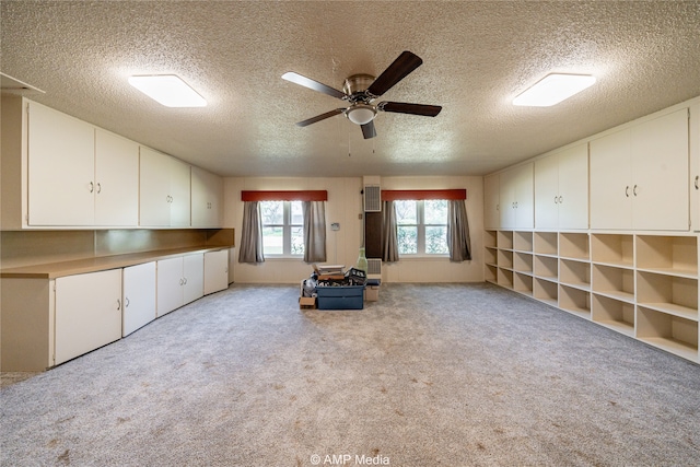 interior space with light carpet, ceiling fan, and a textured ceiling