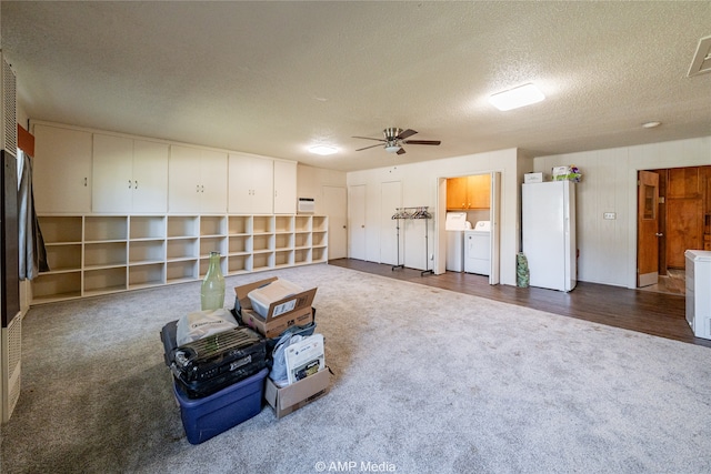 interior space featuring ceiling fan, washing machine and clothes dryer, hardwood / wood-style floors, and a textured ceiling