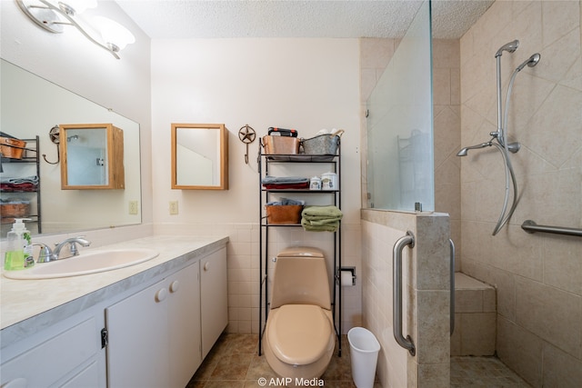 bathroom with vanity, tiled shower, a textured ceiling, tile patterned floors, and toilet