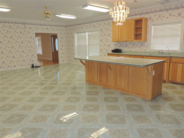 kitchen with sink, a center island, hanging light fixtures, ceiling fan with notable chandelier, and ornamental molding