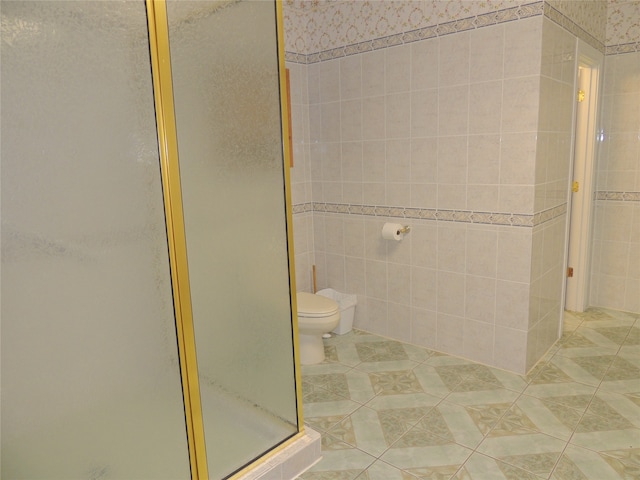 bathroom featuring tile patterned flooring, a shower with shower door, and toilet