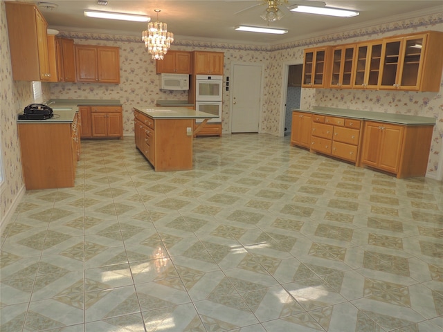 kitchen with crown molding, a kitchen island, decorative light fixtures, and white appliances