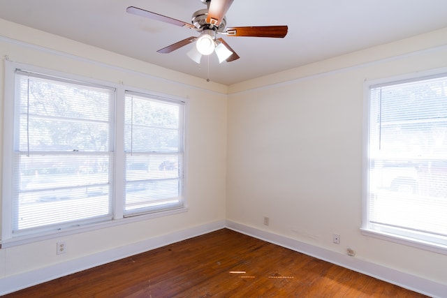 empty room with ceiling fan, dark hardwood / wood-style flooring, and a healthy amount of sunlight