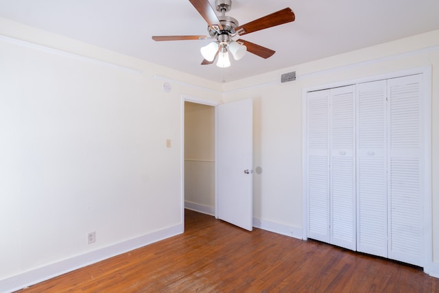 unfurnished bedroom featuring ceiling fan, a closet, and dark wood-type flooring