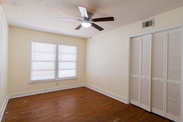 unfurnished bedroom featuring ceiling fan, a closet, and dark wood-type flooring