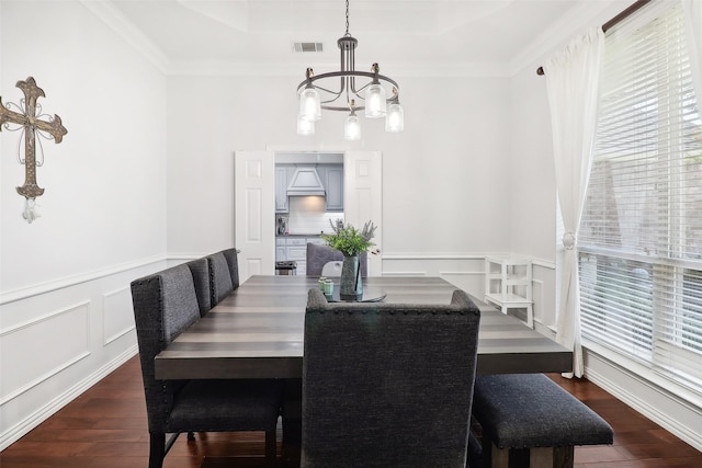 dining room with crown molding, dark wood-type flooring, an inviting chandelier, and a tray ceiling