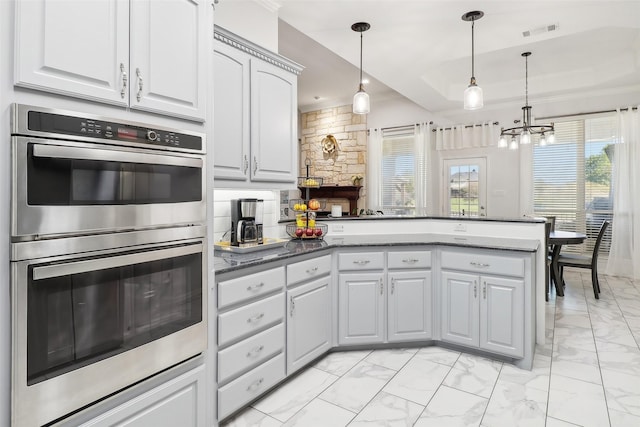 kitchen featuring hanging light fixtures, stainless steel double oven, a notable chandelier, and white cabinetry