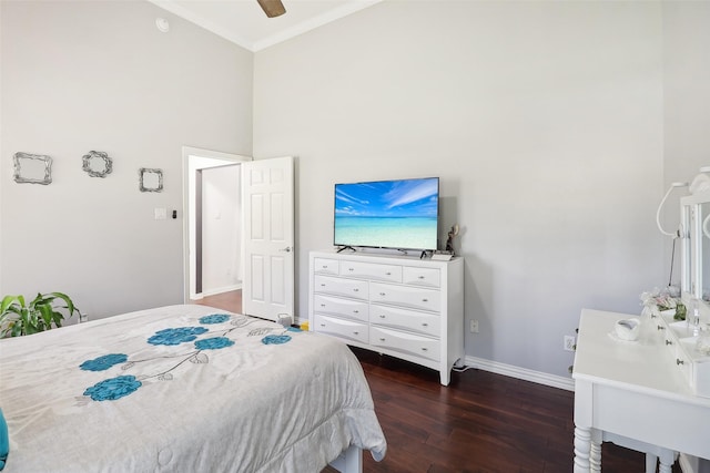 bedroom with ceiling fan, dark hardwood / wood-style flooring, ornamental molding, and a high ceiling