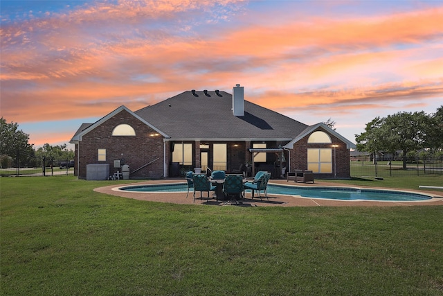 back house at dusk with a patio area, a fenced in pool, and a yard