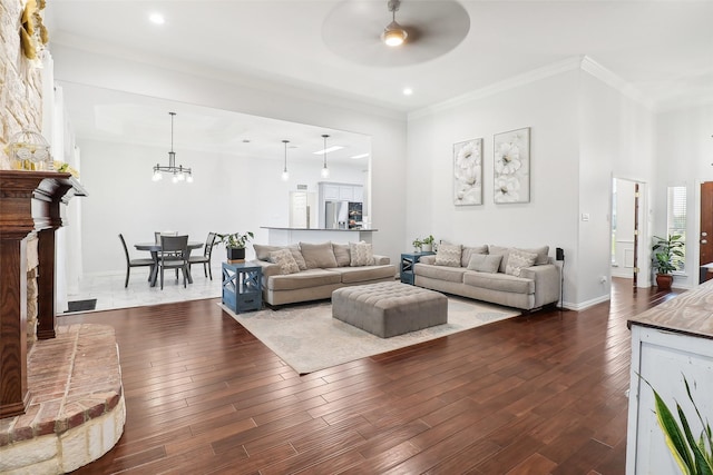 living room with dark hardwood / wood-style flooring, ceiling fan with notable chandelier, and ornamental molding