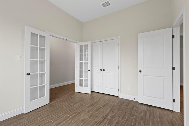 unfurnished bedroom featuring a closet, french doors, and dark hardwood / wood-style floors