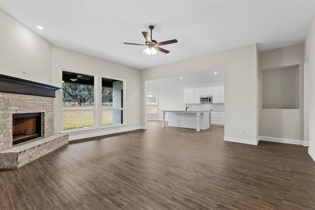 unfurnished living room featuring dark hardwood / wood-style floors, ceiling fan, and a fireplace