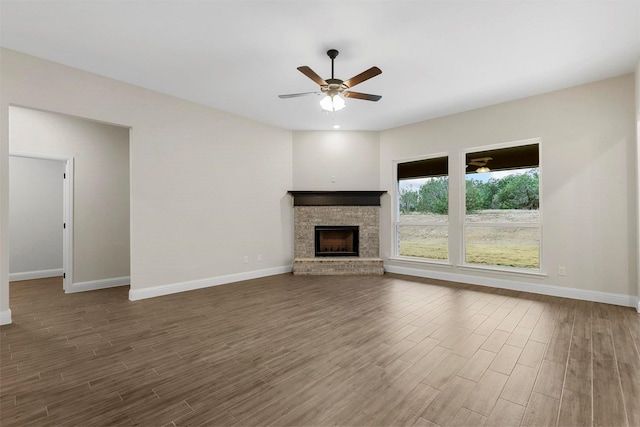 unfurnished living room featuring a fireplace, dark hardwood / wood-style flooring, and ceiling fan