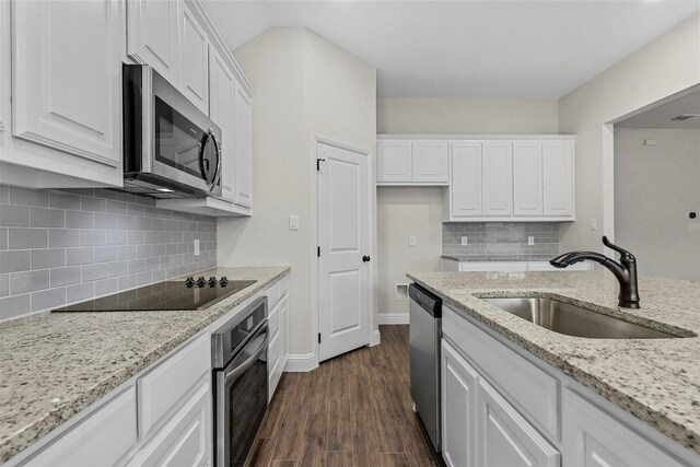 kitchen with white cabinetry, sink, decorative backsplash, a center island with sink, and hardwood / wood-style flooring