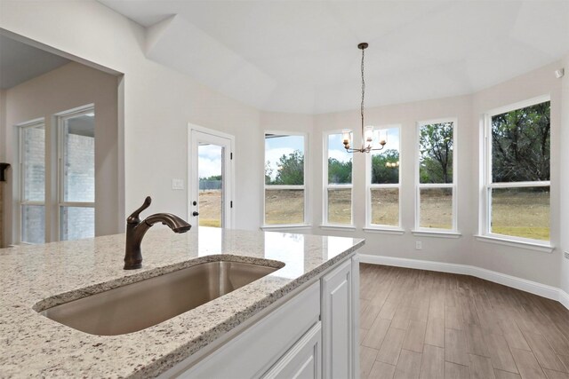 kitchen featuring sink, hardwood / wood-style flooring, white cabinetry, and an island with sink