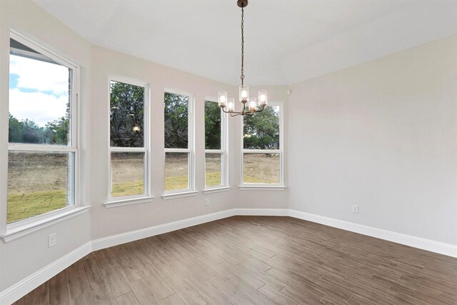 unfurnished dining area with hardwood / wood-style floors, a notable chandelier, and a healthy amount of sunlight