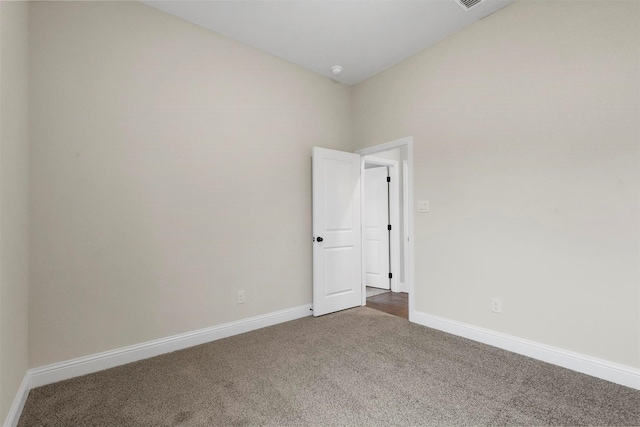 empty room featuring dark carpet and lofted ceiling