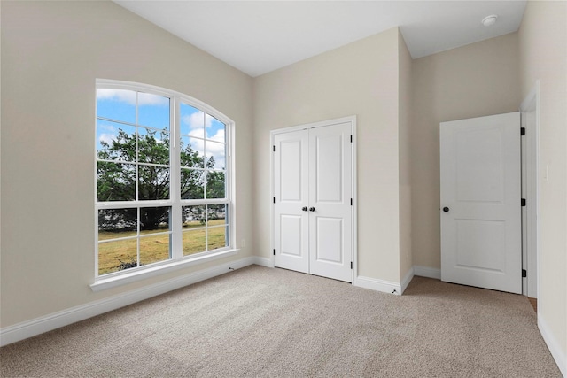 unfurnished bedroom featuring multiple windows, a closet, and light colored carpet