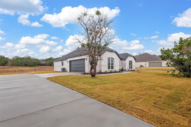 french country style house featuring central air condition unit, a front lawn, and a garage