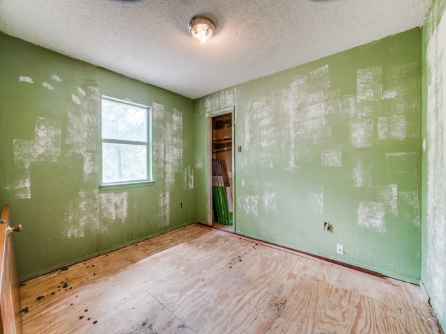 unfurnished room with light hardwood / wood-style flooring and a textured ceiling