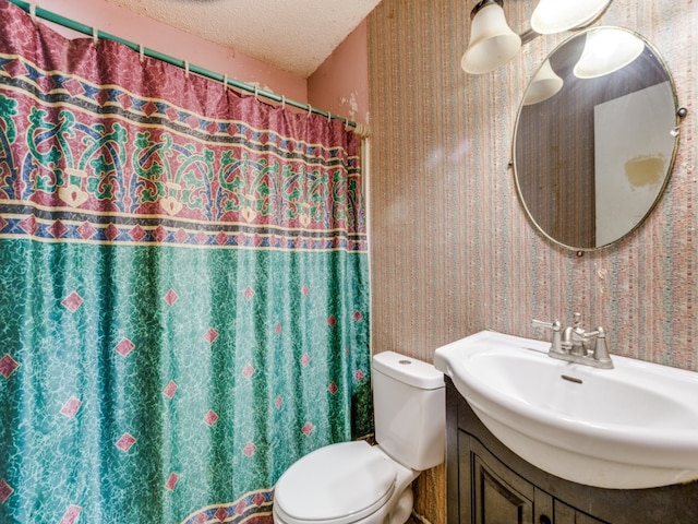 bathroom with a textured ceiling, curtained shower, vanity, and toilet