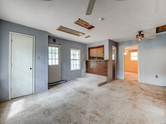 unfurnished living room with a textured ceiling, light carpet, and ceiling fan