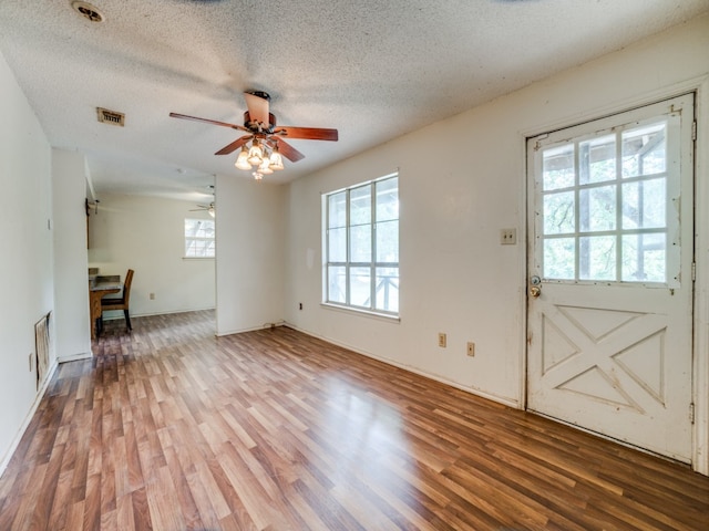 unfurnished living room with ceiling fan, hardwood / wood-style flooring, and a textured ceiling