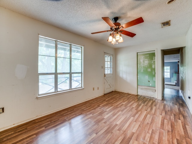 unfurnished room with light hardwood / wood-style flooring, ceiling fan, and a textured ceiling