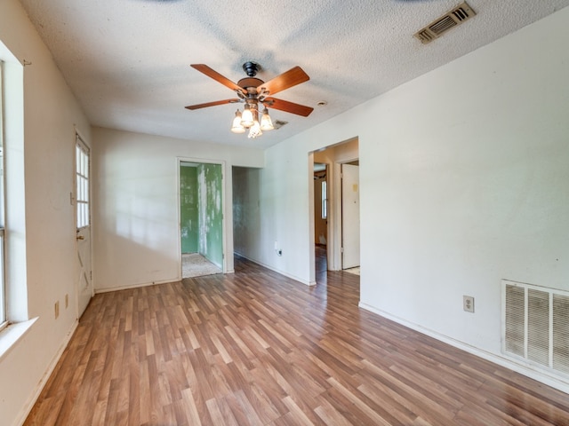 unfurnished room with ceiling fan, a textured ceiling, and light wood-type flooring