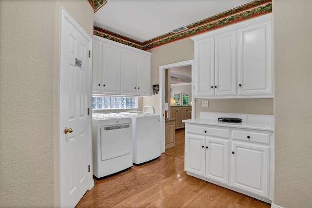 laundry area featuring cabinets, light hardwood / wood-style floors, and washer and clothes dryer