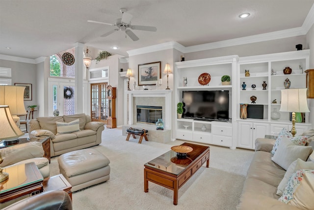 carpeted living room featuring a fireplace, ceiling fan, and crown molding