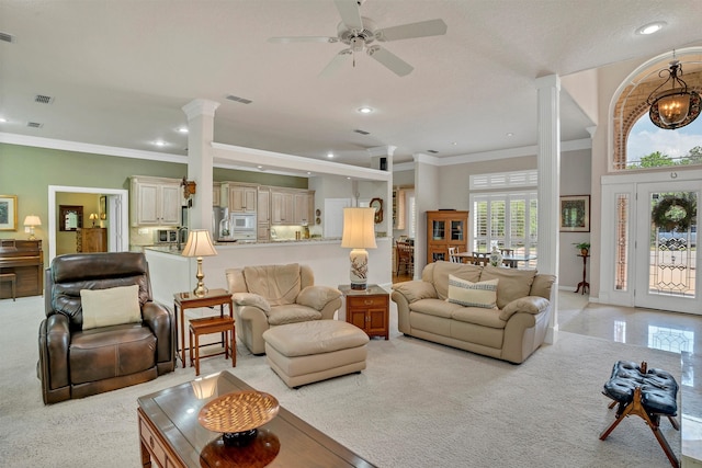 carpeted living room featuring ceiling fan with notable chandelier, decorative columns, and crown molding