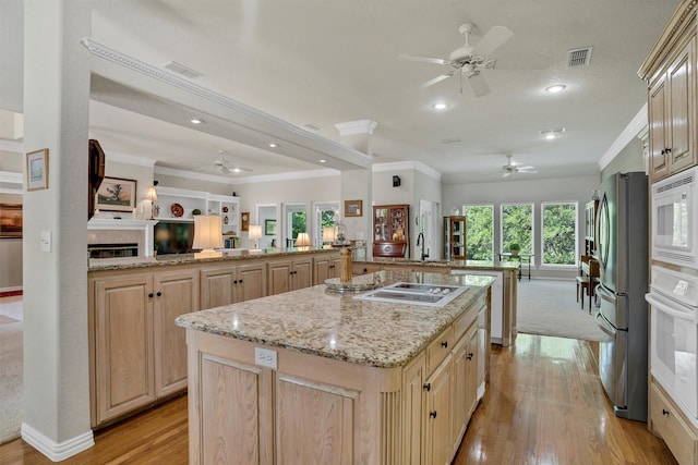 kitchen featuring light brown cabinetry, white appliances, light hardwood / wood-style flooring, and a kitchen island