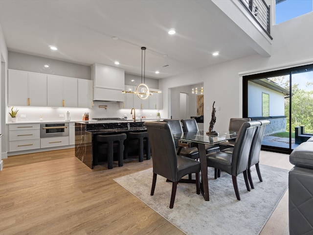 dining room featuring light wood-type flooring, a chandelier, and sink