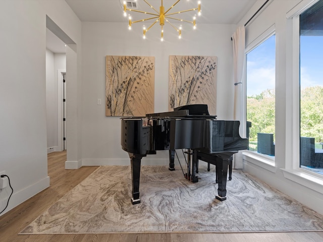 miscellaneous room with a notable chandelier, light hardwood / wood-style floors, and plenty of natural light