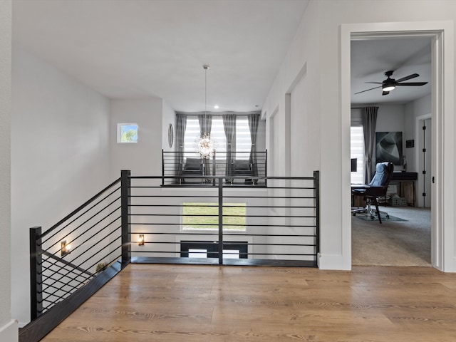 stairway featuring ceiling fan with notable chandelier, a wealth of natural light, and hardwood / wood-style flooring