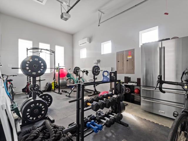 gym with a high ceiling, electric panel, a wall unit AC, and concrete floors